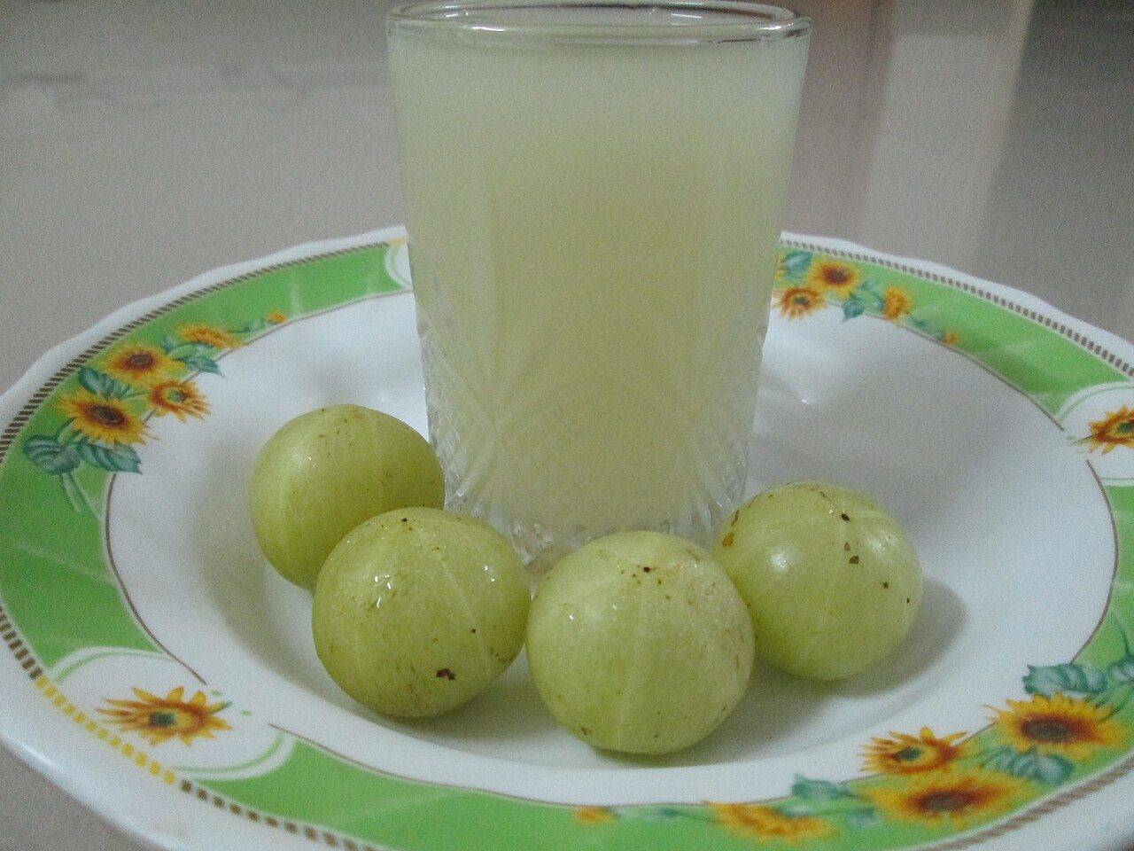 A glass of fresh Amla juice with gooseberries
