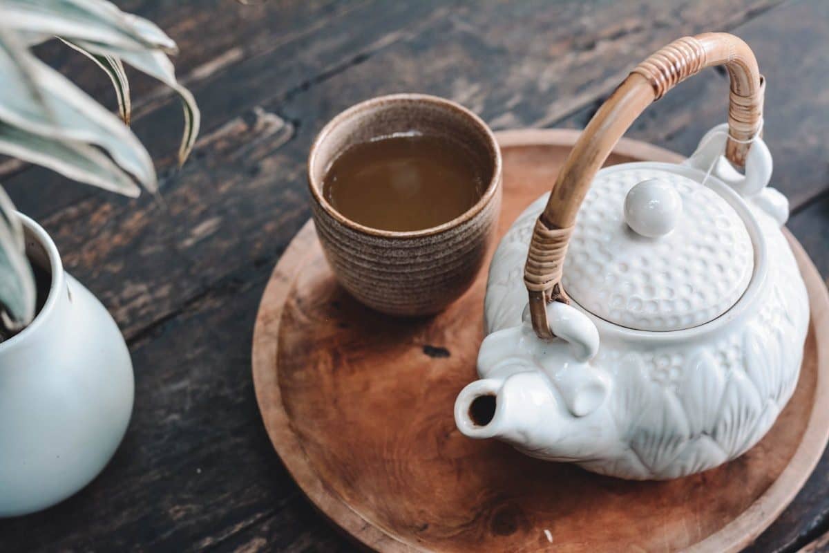 A traditional pot and cup of herbal infusion, poured by hand